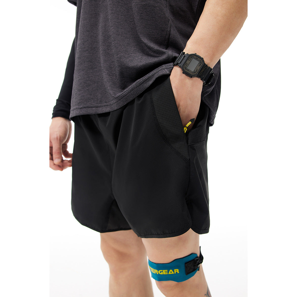 Close-up of black shorts showing the curved side pocket and contrasting textured panel.