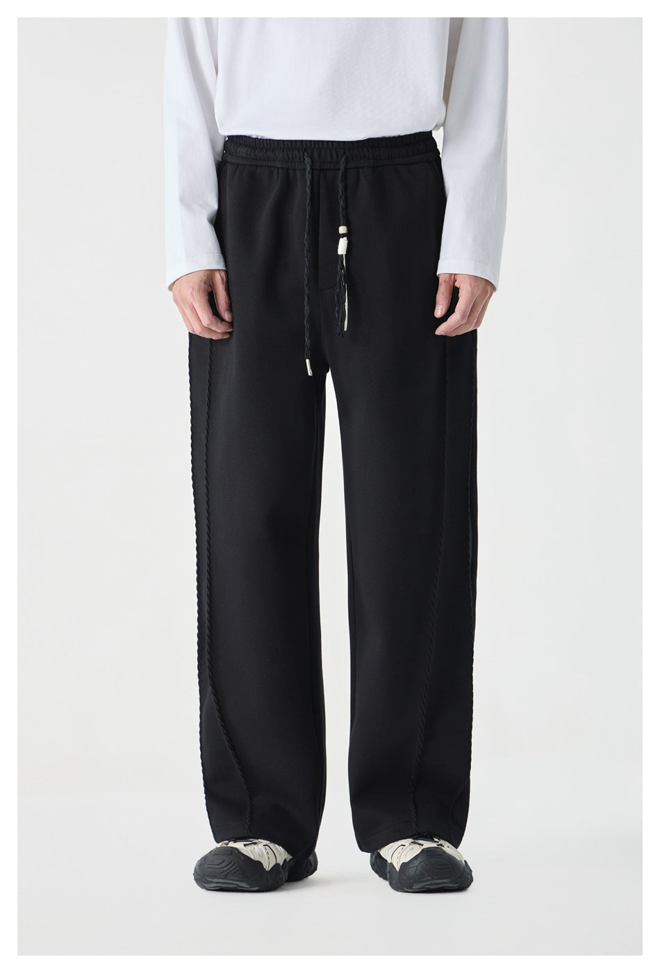 Front view of a model wearing black wide-leg drawstring pants with a braided drawstring waist.