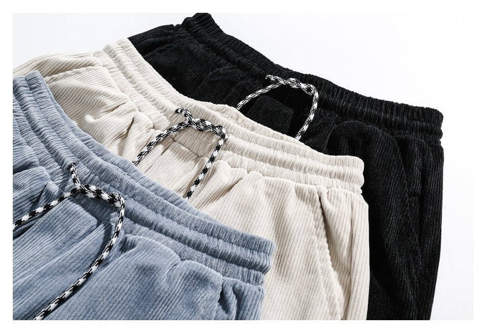 Three pairs of ribbed drawstring pants in light blue, cream, and black, arranged together.
