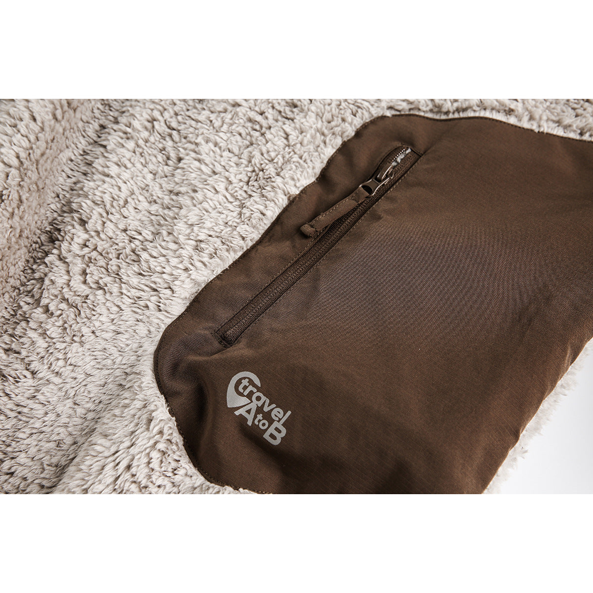 Close-up of a brown zip pocket and light-colored logo on the plush sweatshirt.