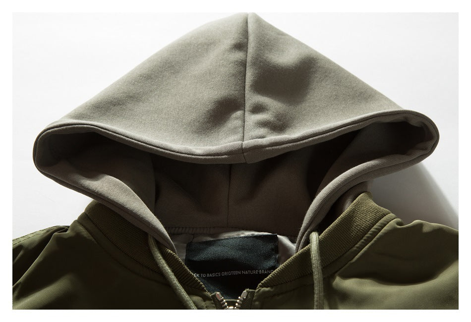 Close-up of an olive jacket collar and pale gray hood, showing the hood lining, drawstrings and neck label.