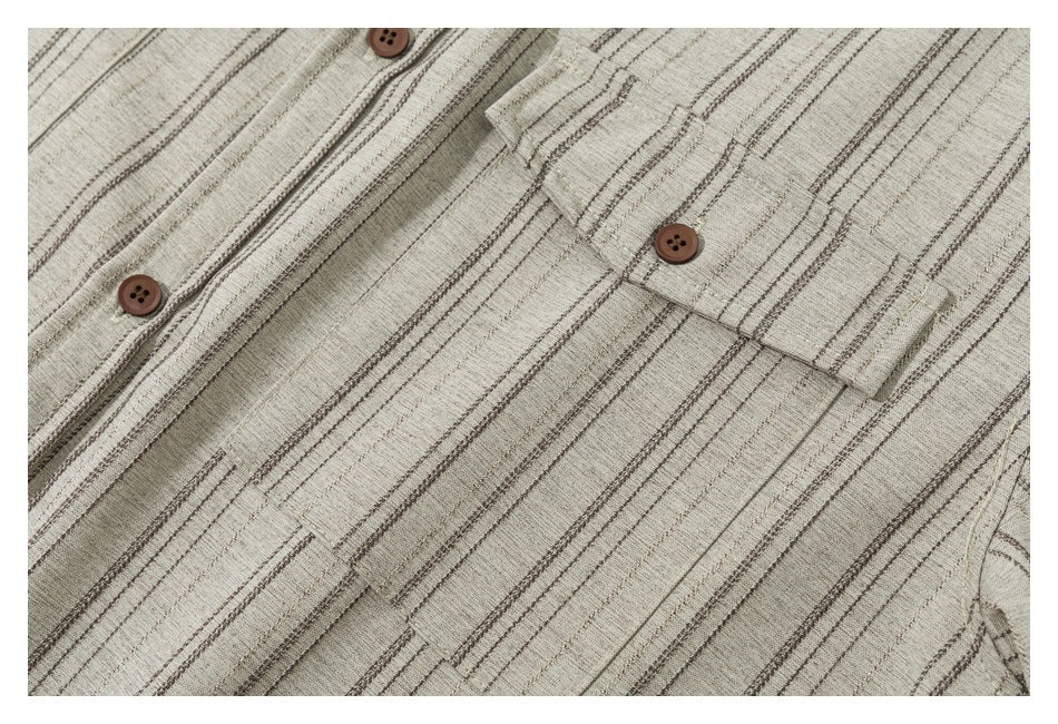 Close-up of a beige striped shirt showing its brown buttons, button placket, and chest pocket.