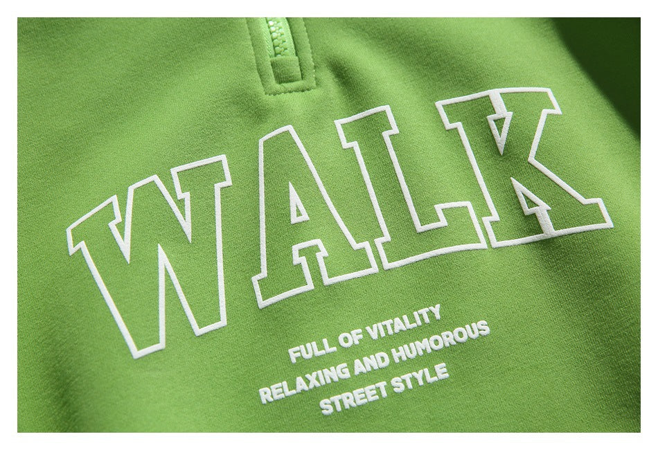 Close-up of white outlined “WALK” lettering and smaller English text printed on the bright green pullover.