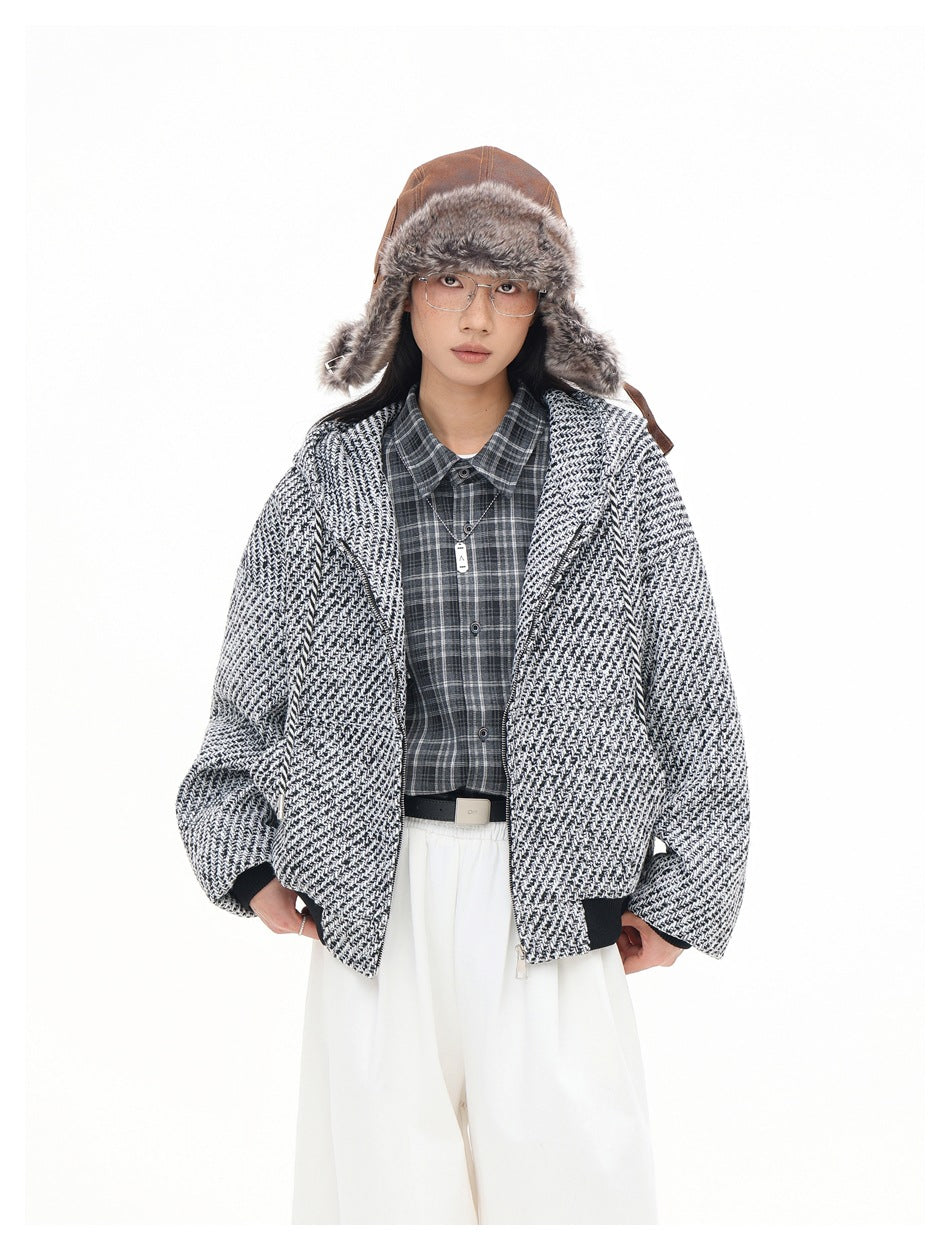 Model wearing the black and white tweed-textured hooded zip jacket open over a plaid shirt with white pants