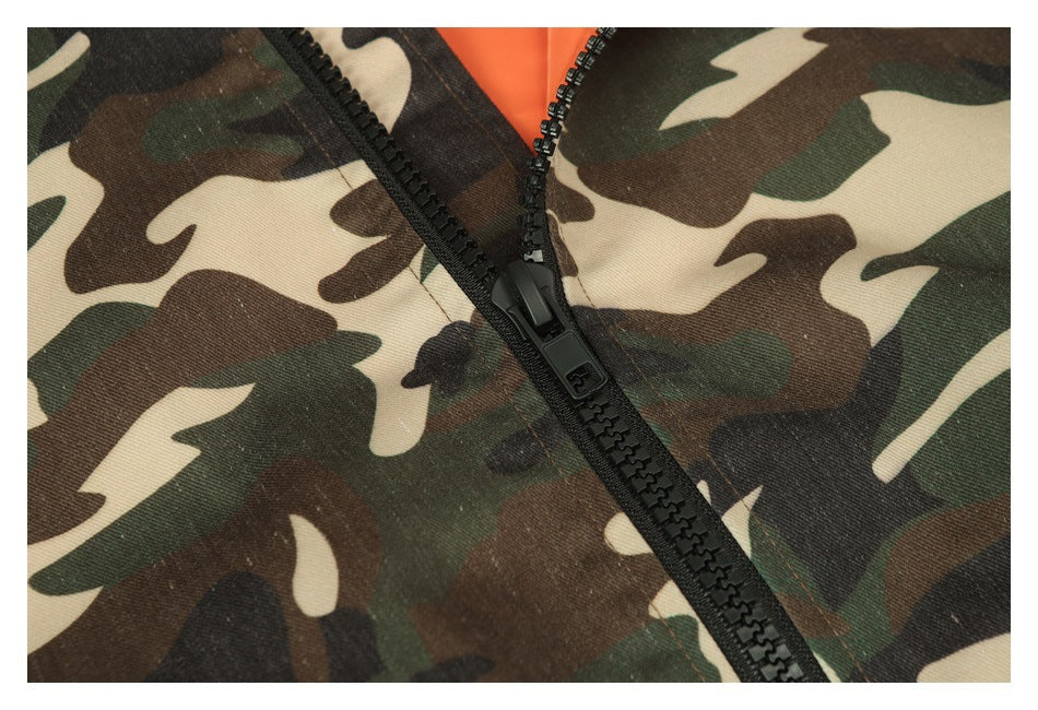 Close-up of a black zipper on the jacket’s green, brown, black, and tan camouflage fabric.