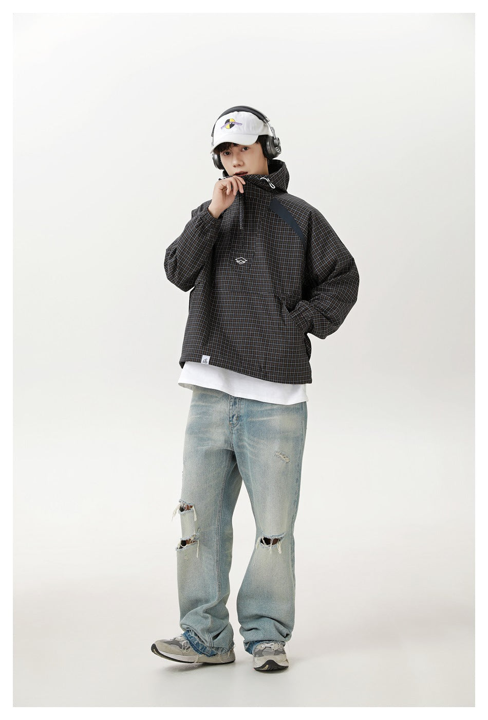 Full-length model wearing a dark grid-plaid hooded pullover jacket with a front pouch pocket.