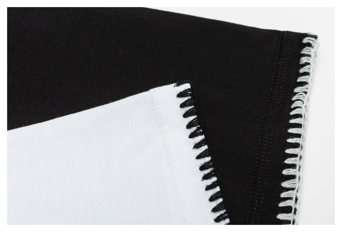 Close-up comparing black and white garment fabric edges finished with contrasting loop stitching.