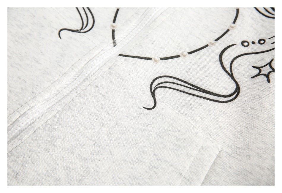 Close-up of a black graphic and white zipper on light gray heather fabric, with part of a pocket visible.