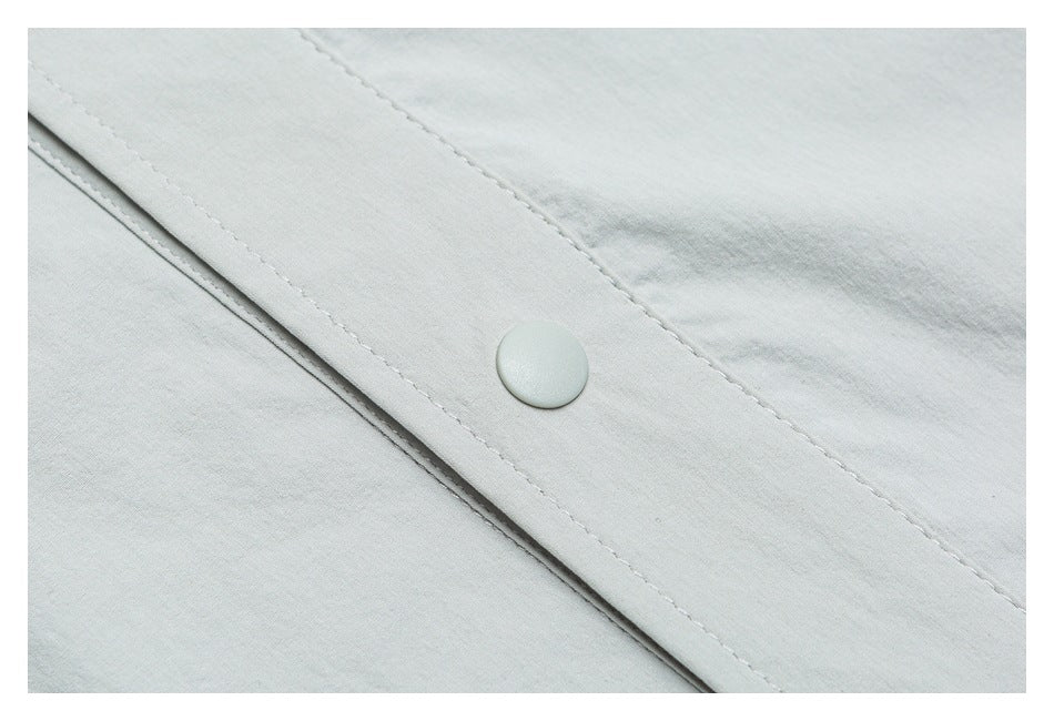 Close-up of a pale gray snap button on a stitched garment placket.
