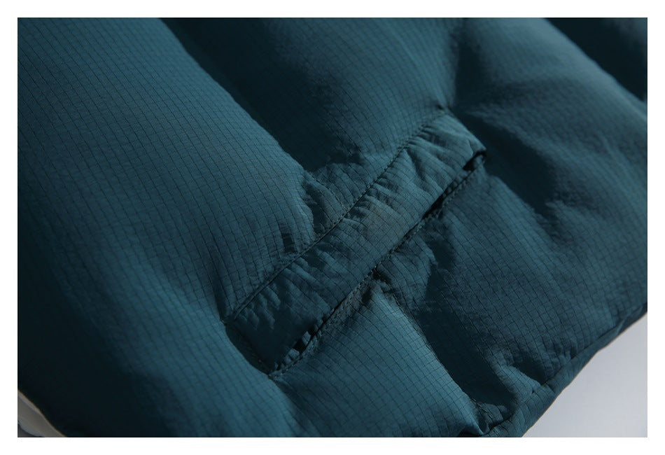 Close-up of dark teal ripstop-textured fabric with a stitched folded seam.