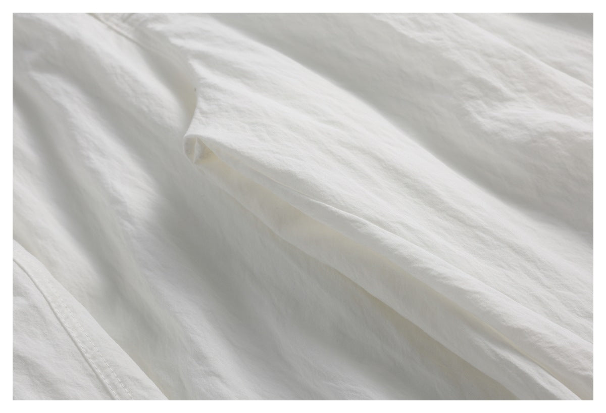 Close-up of an off-white trouser leg with a folded edge and visible stitching.
