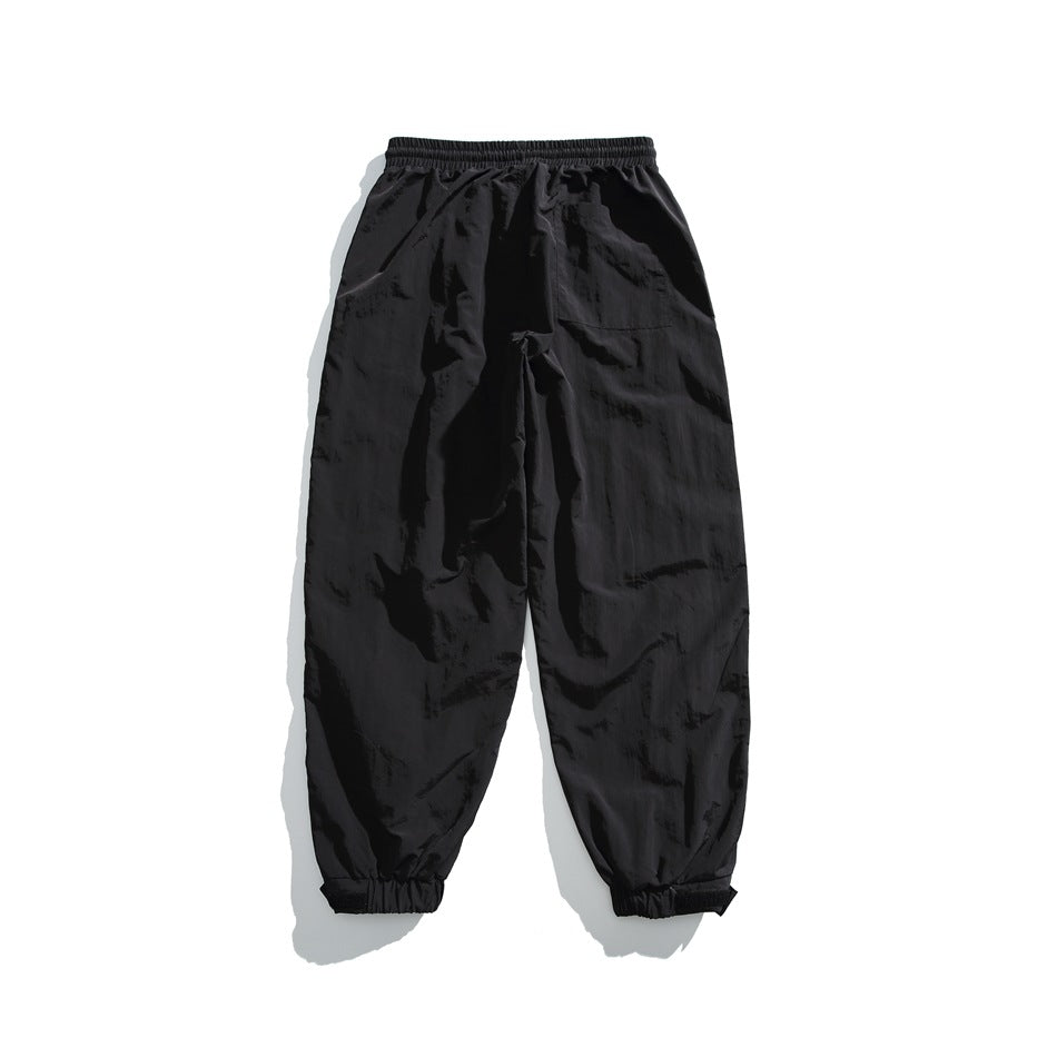 Back view of black loose-fit pants with an elastic waist, single patch pocket, and elastic cuffs.