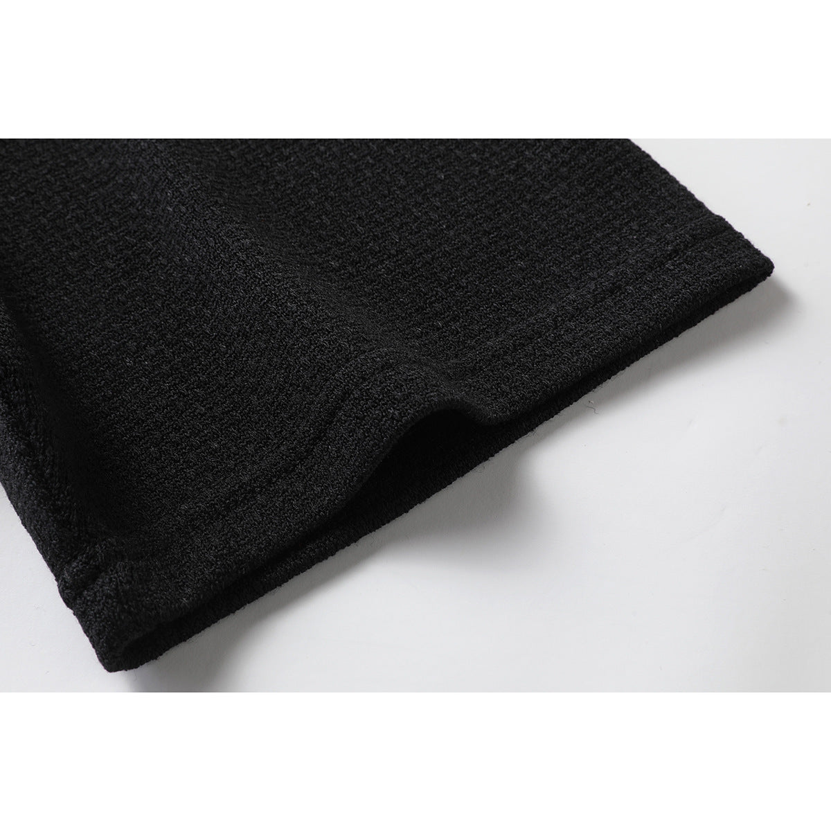 Close-up of the hem and fabric texture of a black T-shirt.