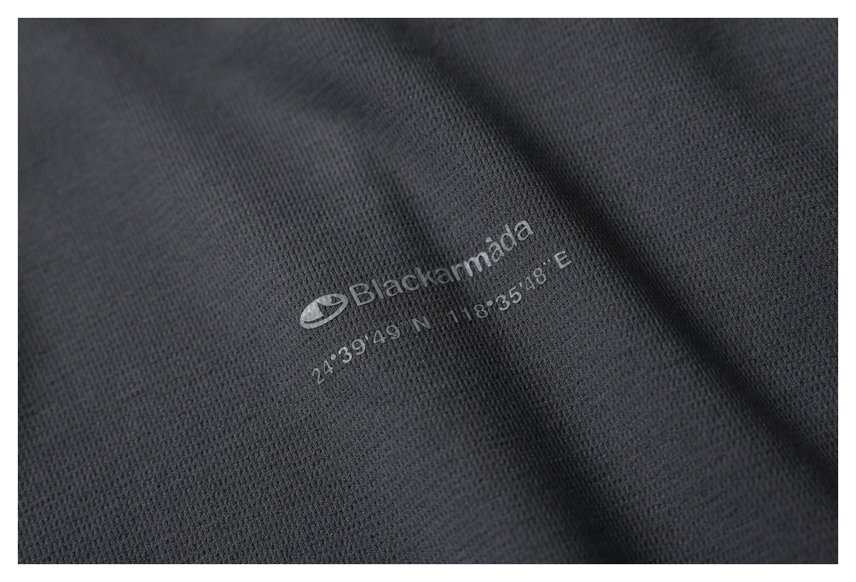 Close-up of charcoal textured fabric with a printed Blackarmada logo and coordinates.