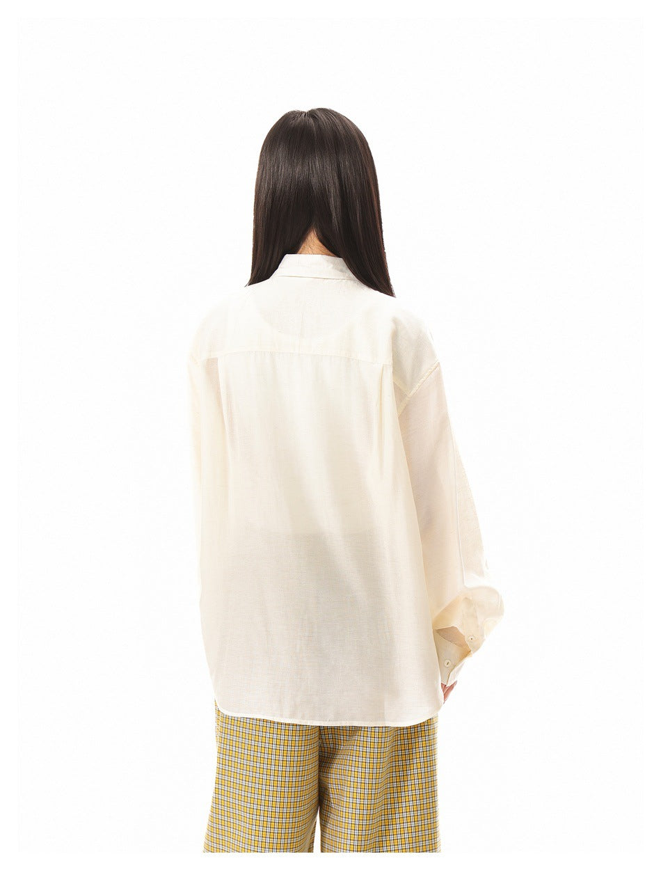 Back view of a model wearing an oversized ivory button-up shirt with yellow checked trousers.