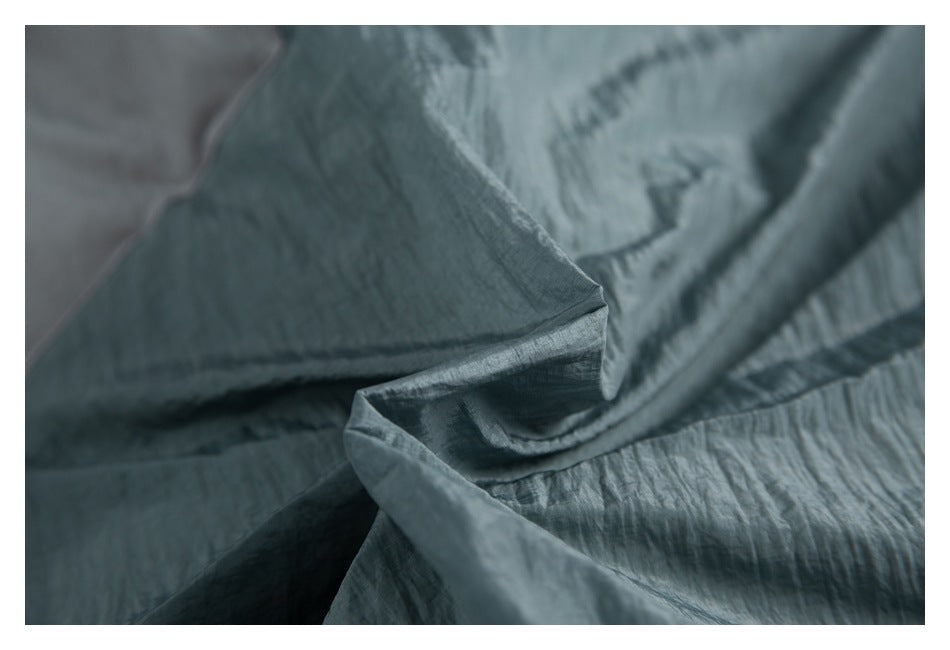 Macro view of wrinkled teal garment fabric and stitched seams.