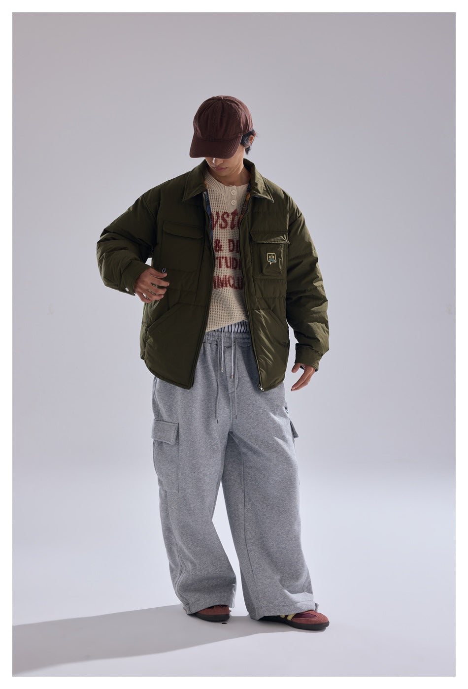 Full-length model wearing an olive quilted jacket with flap pockets and loose gray cargo pants.