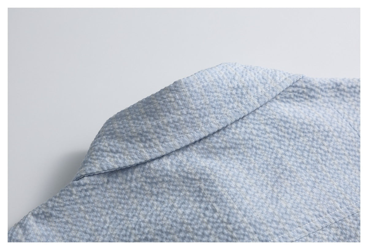 Close-up of a folded, stitched edge on light blue-gray textured fabric.