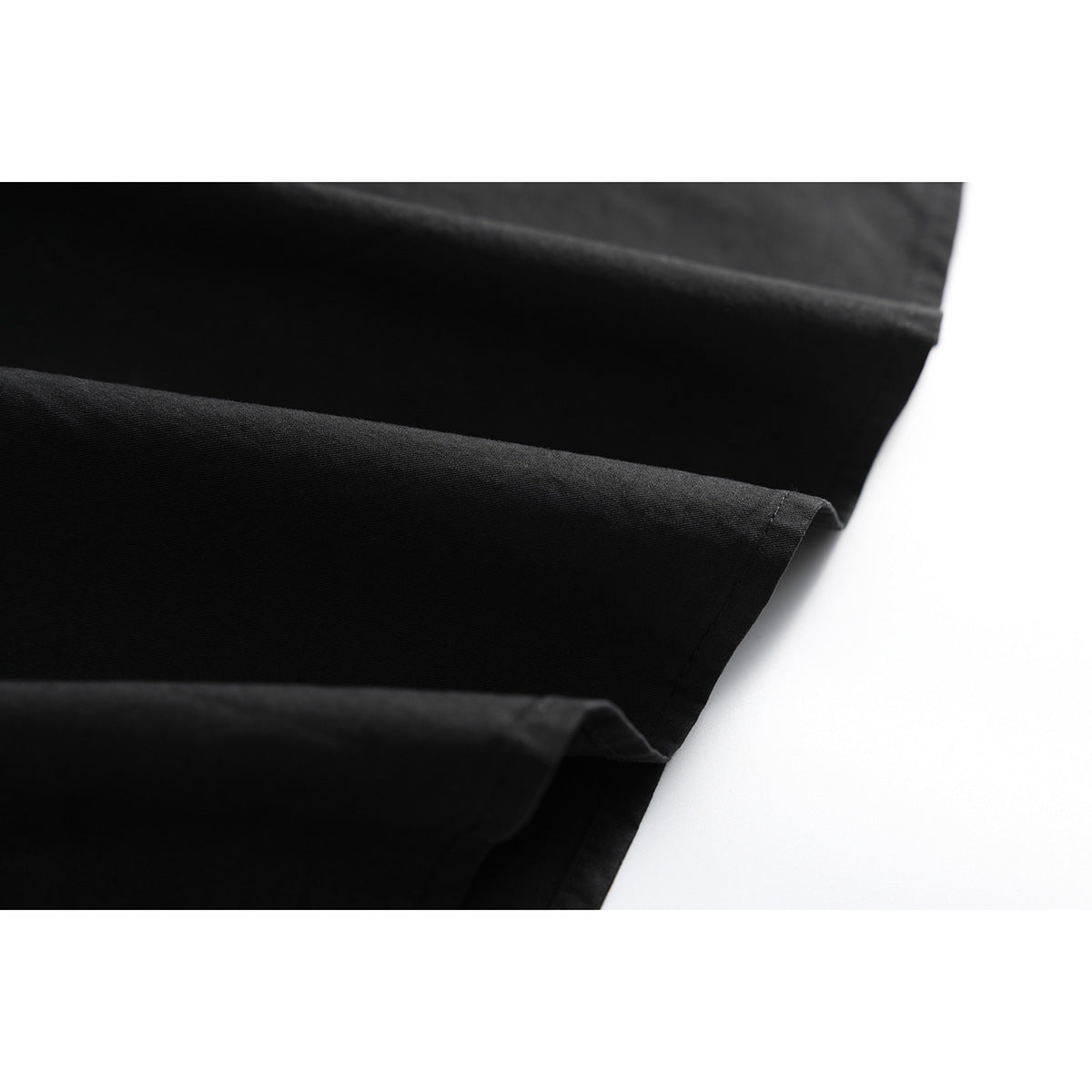 Close-up of the folded hem and smooth black fabric of a shirt.