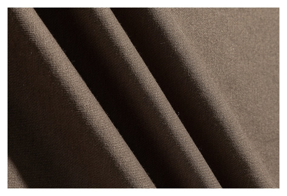 Macro view of taupe sweatshirt fabric draped into folds, showing its surface texture.