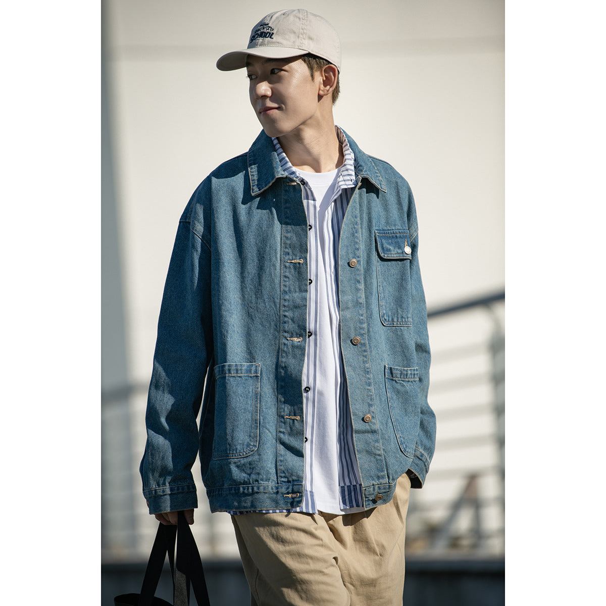 Model wearing a blue denim jacket with multiple patch pockets over a striped shirt, shown from the waist up.