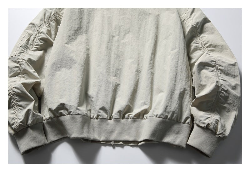 Cropped back view of a light stone-gray jacket with gathered sleeves, a ribbed hem, and ribbed cuffs.