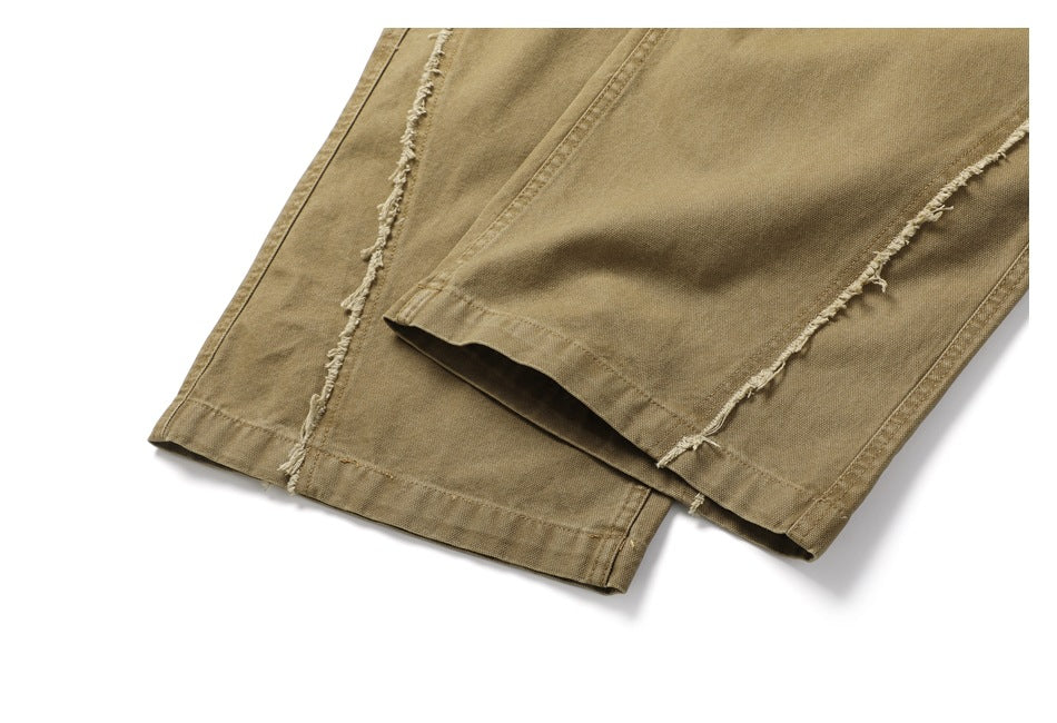 Close-up of khaki trouser hems and frayed seam detailing along the legs.