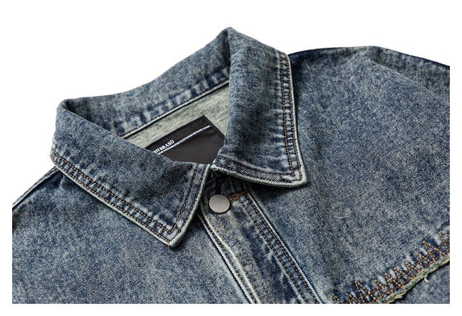 Close-up of the pointed collar and snap-button placket on a blue acid-wash denim jacket.