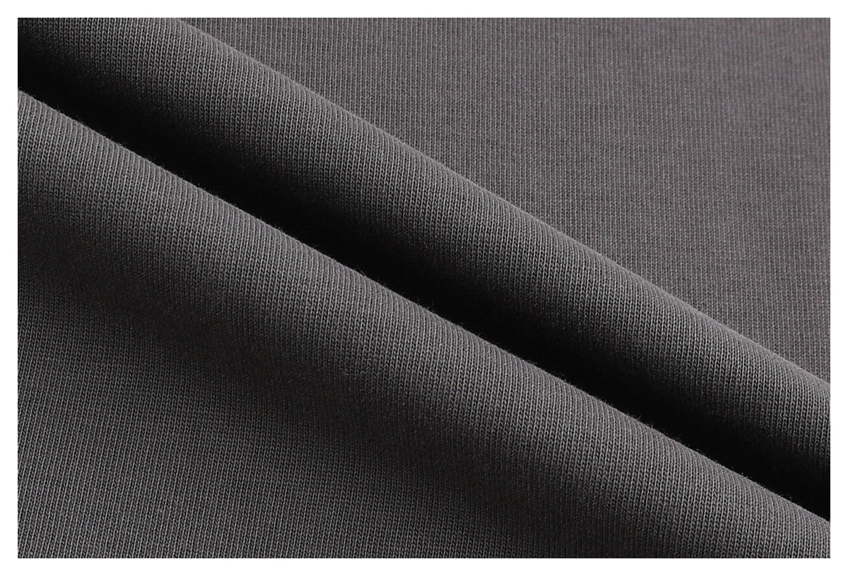 Close-up of dark gray knit fabric draped in folds, showing its fine surface texture.