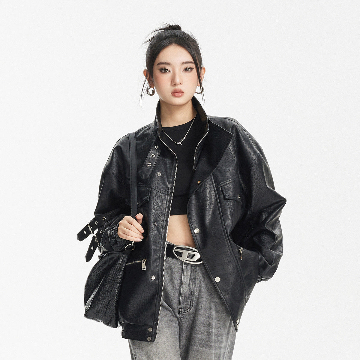 Model wearing an oversized black embossed-pattern jacket with a high collar, zip pockets and sleeve straps.