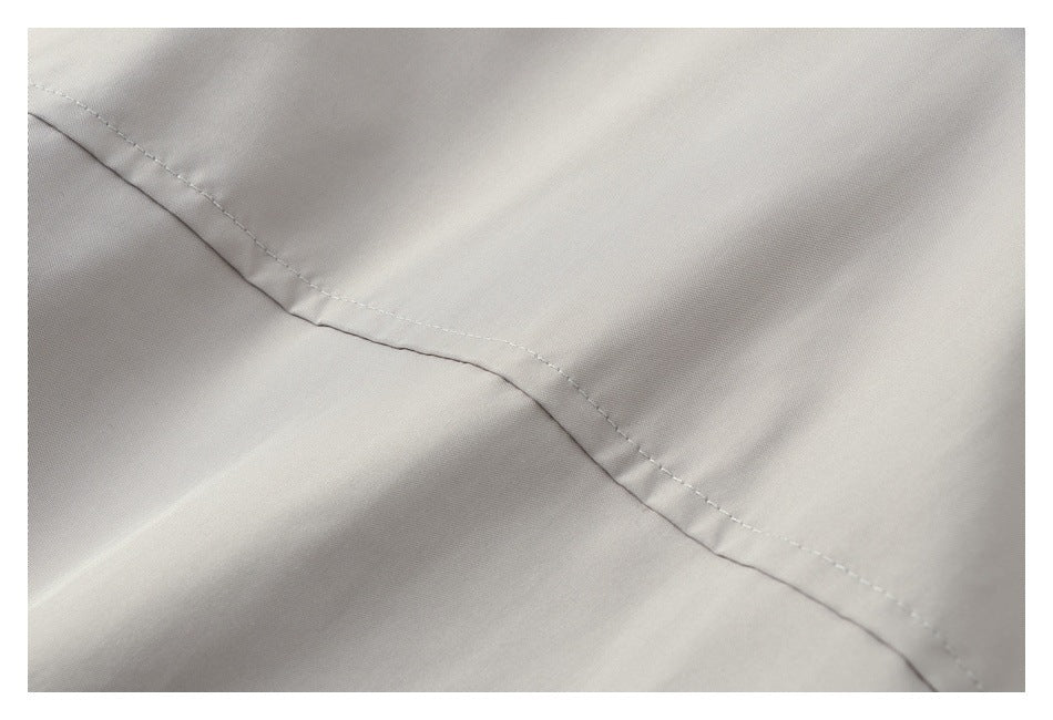 Close-up of a curved stitched seam on smooth light gray fabric.