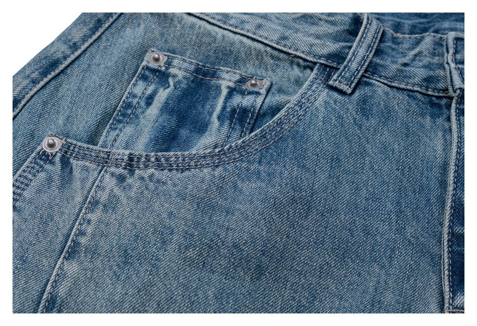 Close-up showing the coin pocket, rivets and stitching on faded blue jeans.