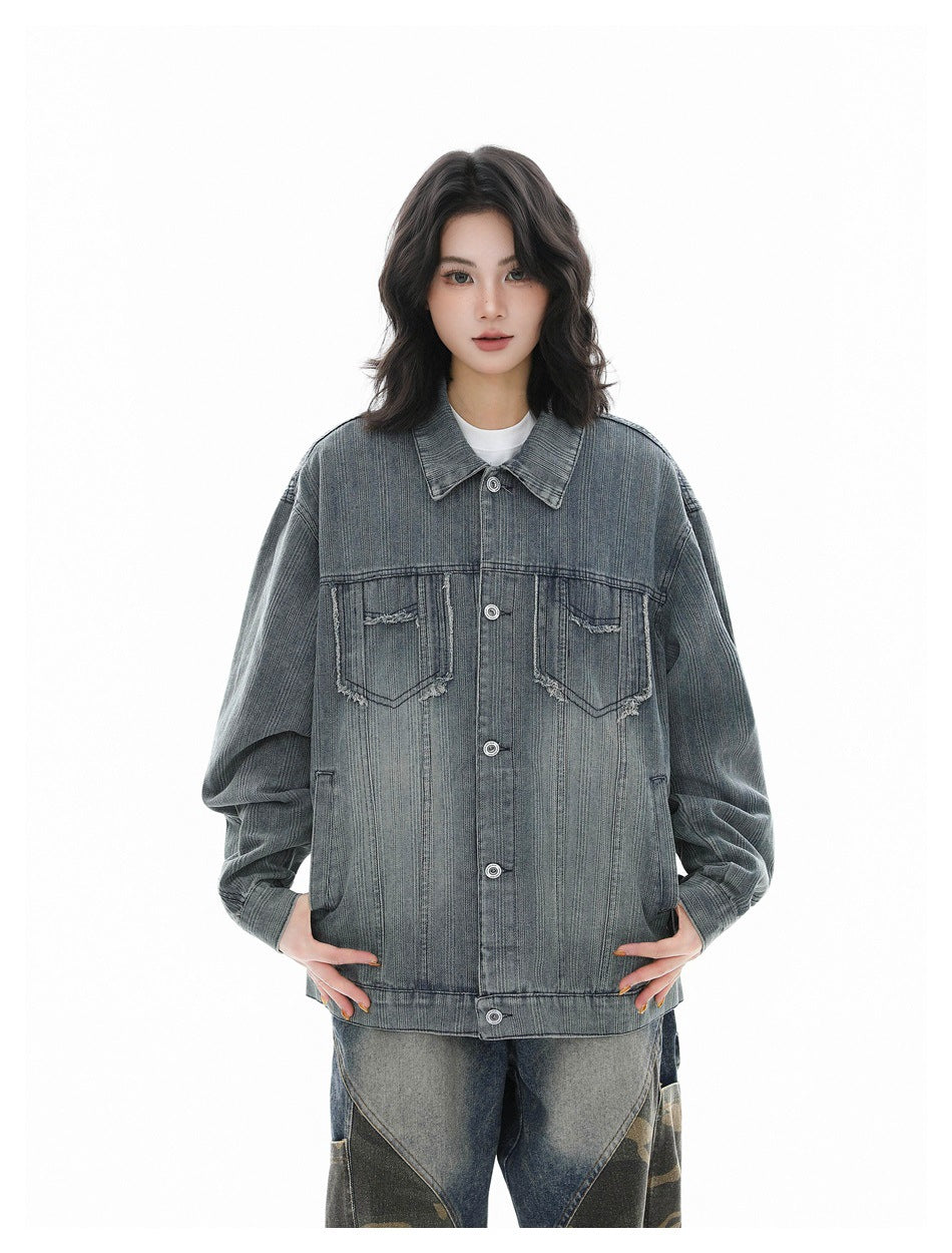 Front view of a model wearing an oversized blue-gray denim jacket with distressed chest pockets.