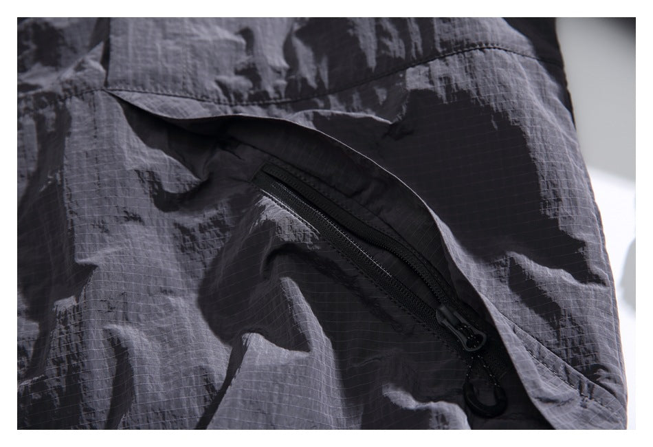 Close-up of a slanted black zip pocket beneath a flap on the charcoal jacket.
