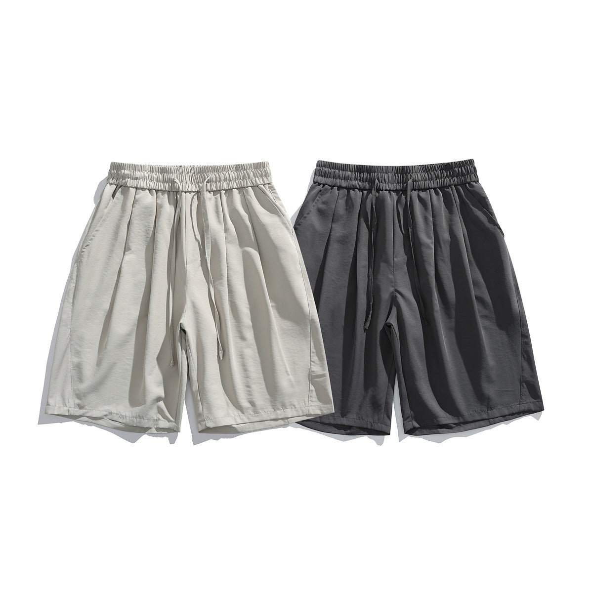 Front view of two loose shorts with elastic drawstring waists, in light beige and charcoal gray.