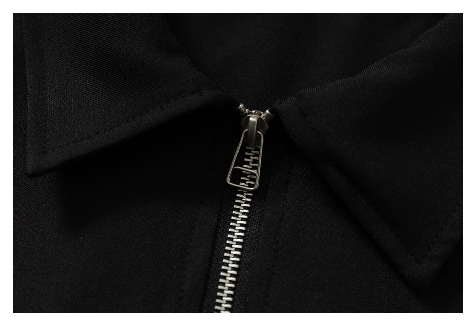 Close-up of the silver zipper and pull beneath the black jacket's collar.