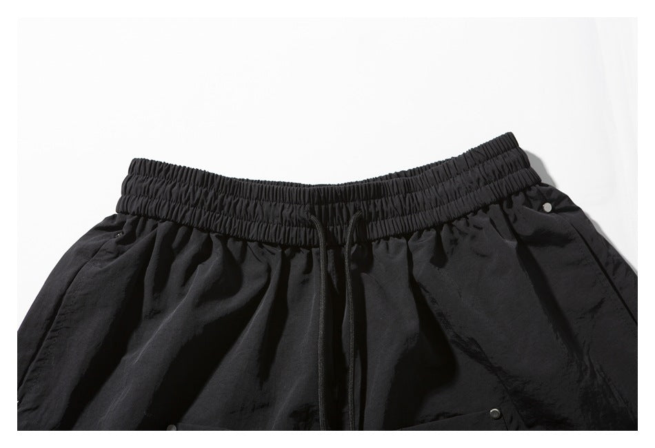 Close-up of black shorts showing the gathered elastic waistband, drawstring, and pocket details.
