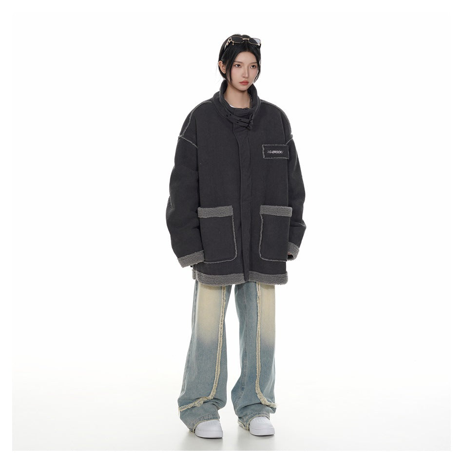 Full-length front view of a model wearing an oversized charcoal high-collar jacket with gray trim and patch pockets.