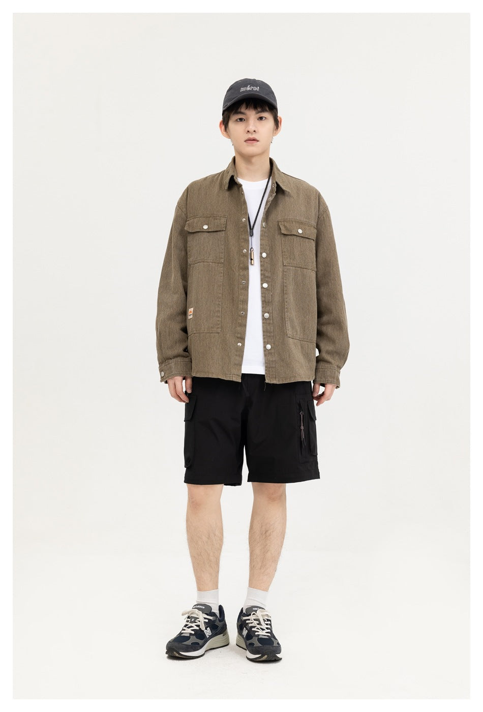 Full-length front view of a model wearing a brown button-front overshirt with chest pockets and black cargo shorts.