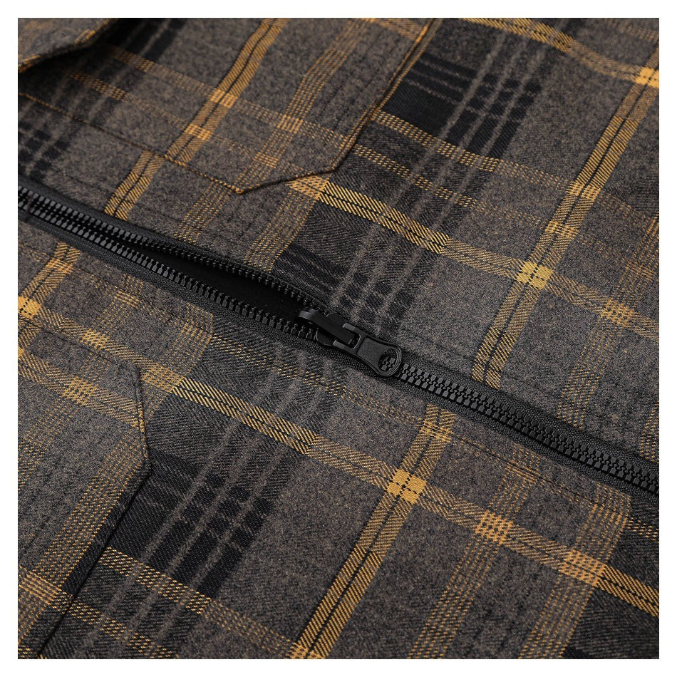 Close-up of a black zipper and slider against the jacket's dark brown and mustard plaid.