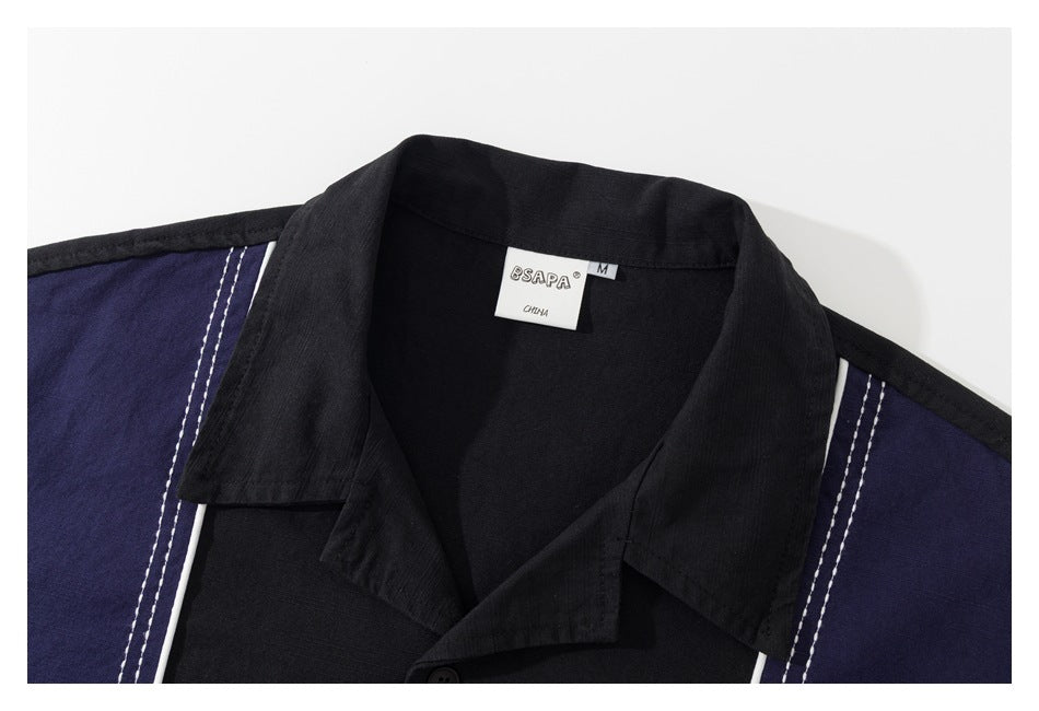 Close-up of a black shirt collar and navy shoulder panels with white piping; the neck label is visible.