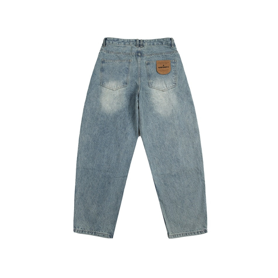 Back flat lay of light blue washed jeans with two patch pockets and a tan leather-look patch