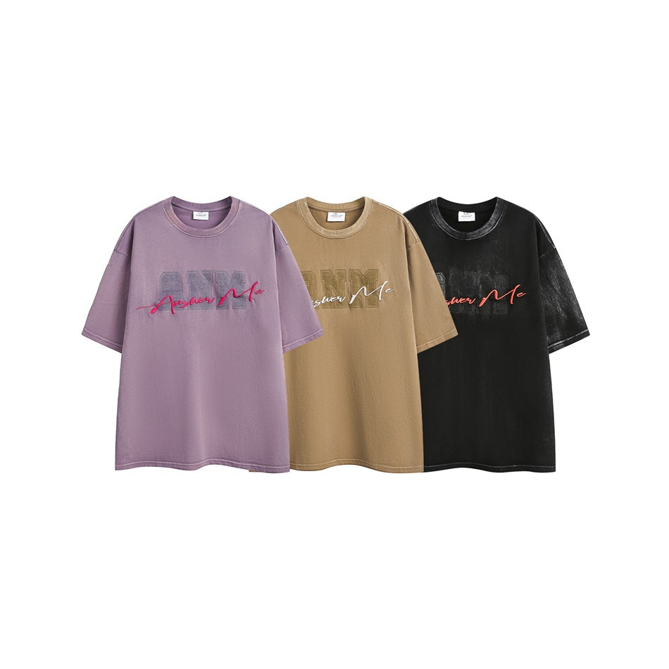 Three short-sleeve graphic T-shirts shown together in lavender, tan and black.