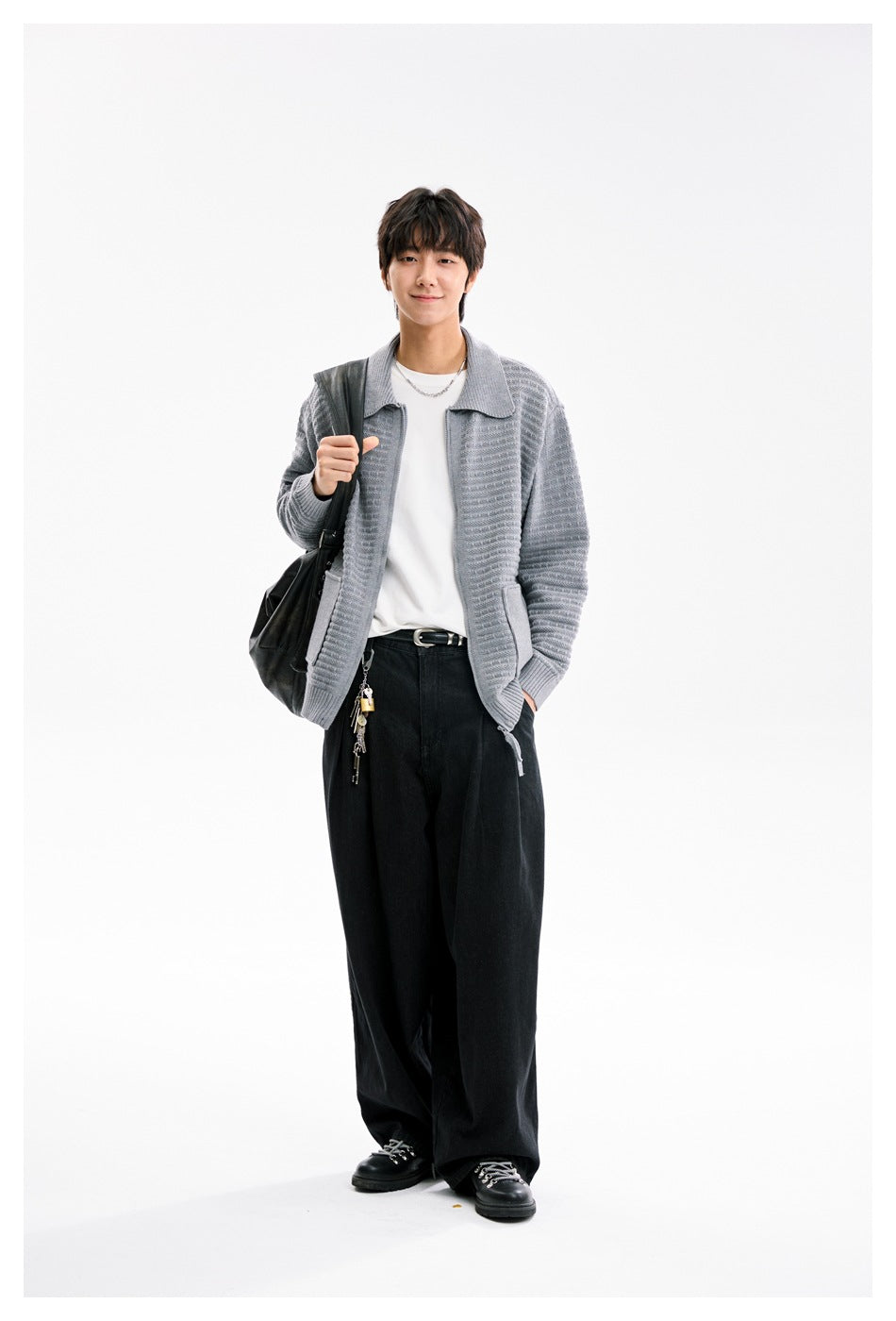 Model wearing gray knit zip cardigan open over a white tee with black wide-leg pants and a black shoulder bag