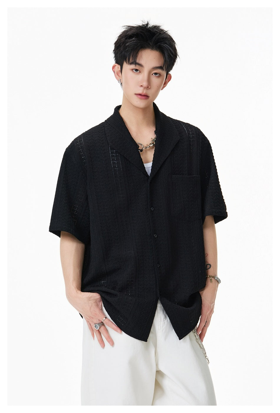 Model wearing a black short-sleeve textured button-up shirt with a notched collar and chest pocket.