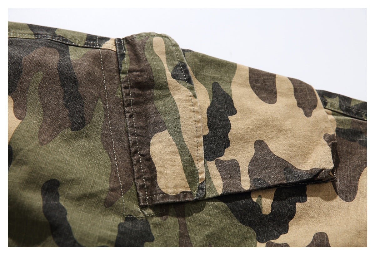 Close-up of a flap pocket and stitching on olive, brown, and tan camouflage trousers.