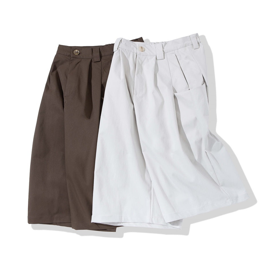 Brown and off-white wide-leg pleated shorts laid together, showing waistband, button and side pocket details