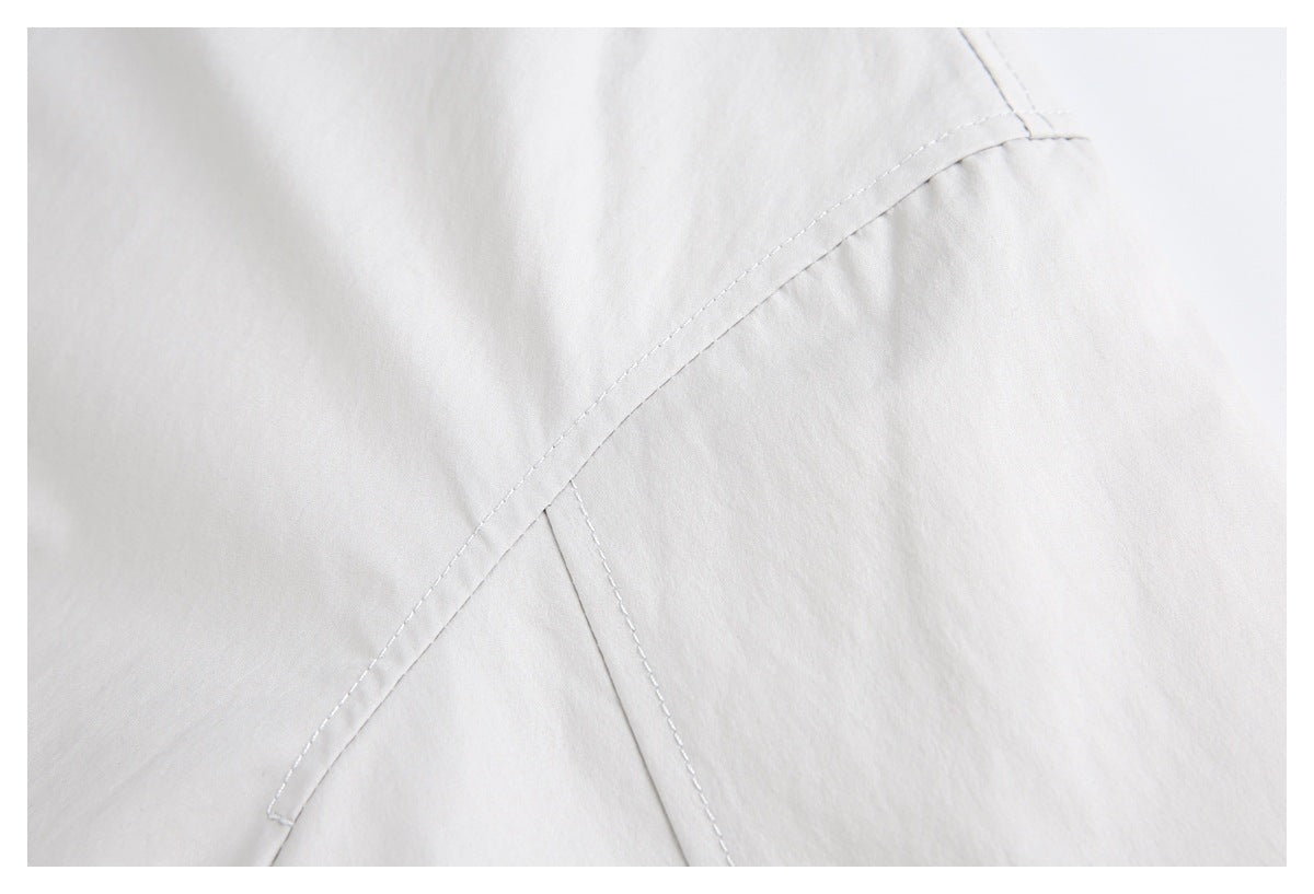 Close-up of pale gray garment fabric with a curved, double-stitched seam.