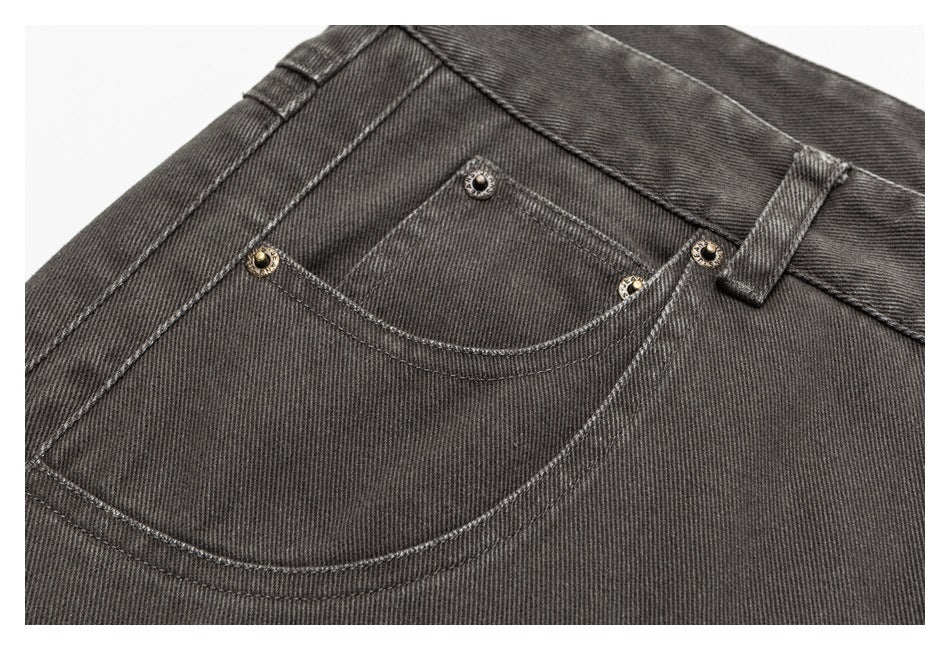 Close-up of charcoal-gray jeans showing a front pocket, coin pocket, contrast stitching, and metal rivets.