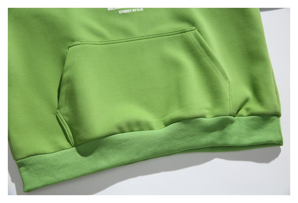 Close-up of a bright green hoodie’s kangaroo pocket and ribbed hem, with small white text near the top.